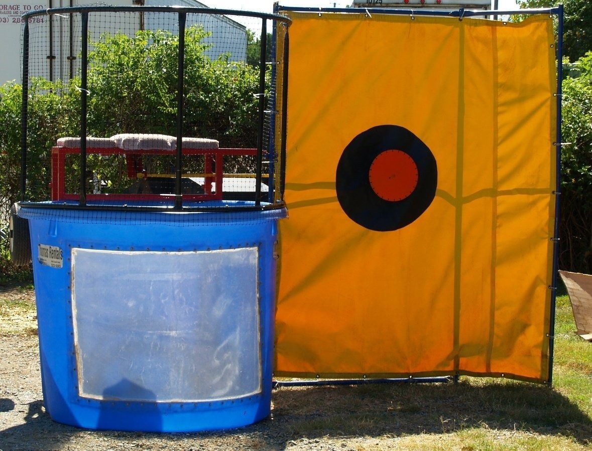 Dunk tank with a blue barrel, a target, and a seat above the water. A person would fall into the water when the target is hit.