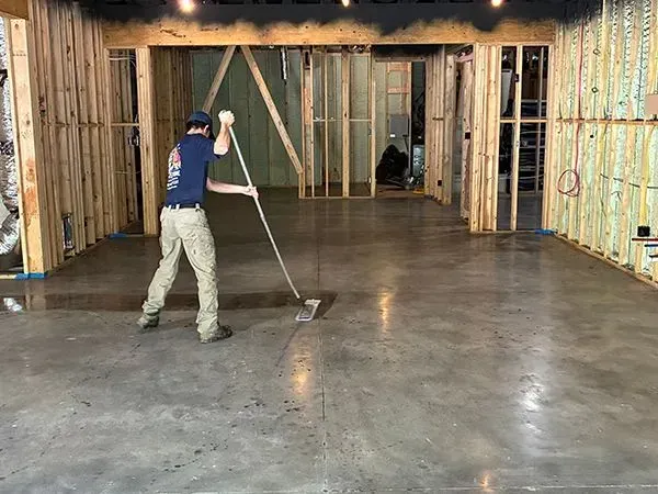 Person smoothing concrete floor in unfinished building.