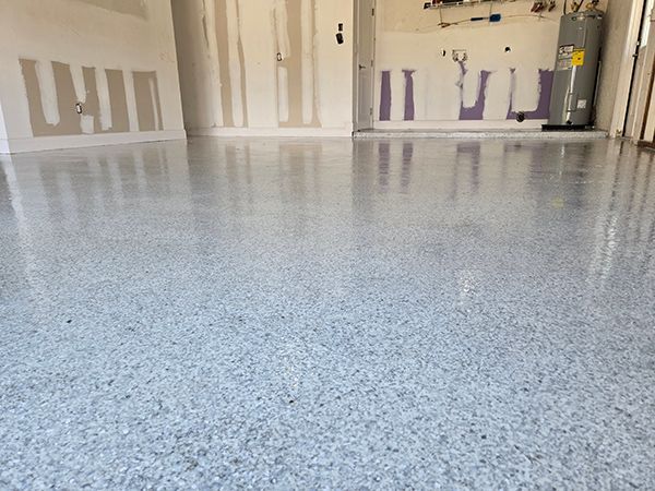 Garage with a shiny, speckled epoxy floor. Bare walls show drywall repair.