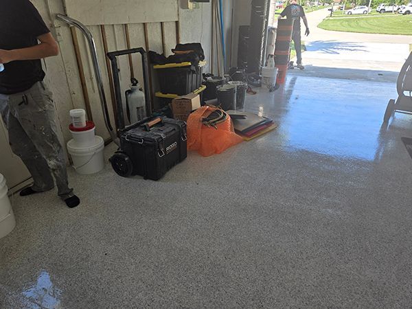 Garage with new epoxy floor, tools, person, and open door.