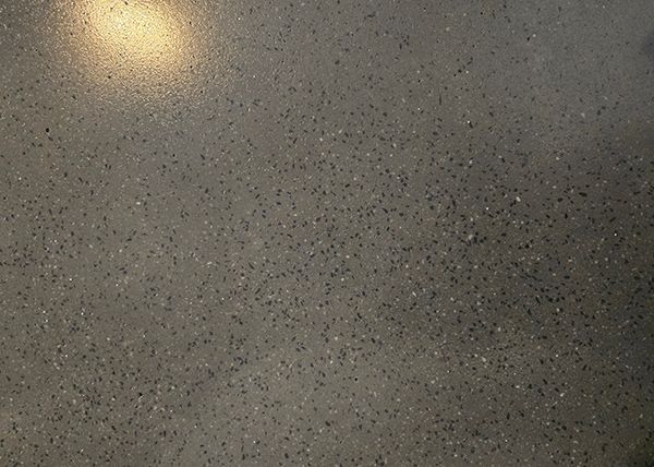 Gray speckled surface with a soft, circular light source in the upper left corner.