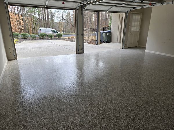 Garage with polished gray floor, open door to driveway, and outside view.