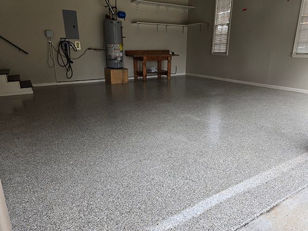 Garage with a gray epoxy floor, water heater, and a workbench.