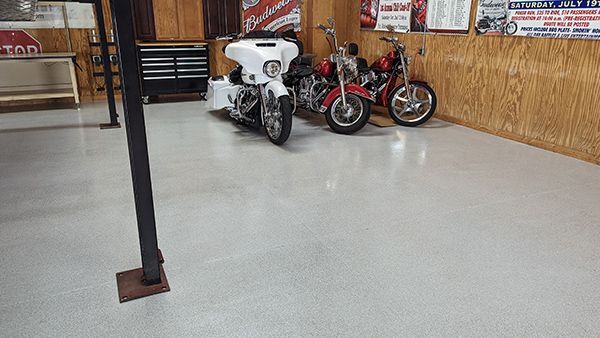 Motorcycles parked in a garage with a light gray floor. Two red and one white motorcycle are visible.