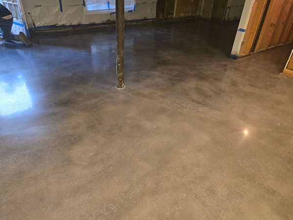 Polished concrete floor in a basement, light brown with subtle color variations, reflecting light.