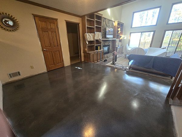 Living room with dark gray concrete floor, wooden built-ins, and large windows.