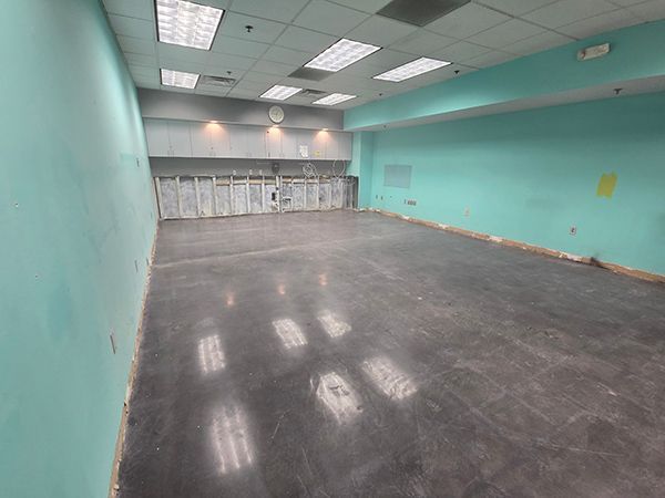 Empty room with teal walls, concrete floor, and exposed infrastructure.