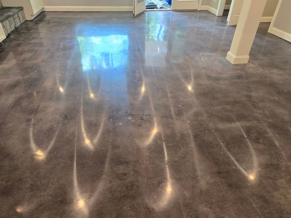 Metallic gray epoxy floor reflecting light with bright streaks.