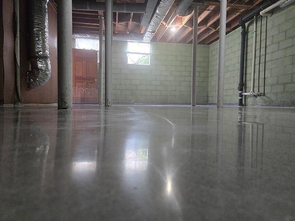 Polished concrete basement floor with exposed beams and cinderblock walls.