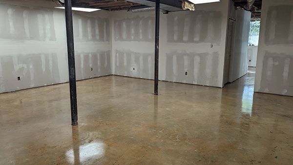 Basement room with polished concrete floor, drywall walls, and support beams.