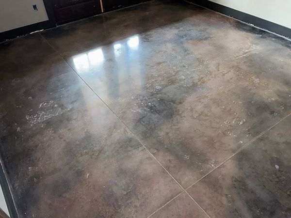 Polished concrete floor with dark and light mottled tones. Reflective, rectangular pattern with black trim.