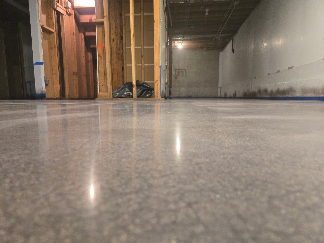 Polished concrete floor in a construction setting with wood framing and white walls.