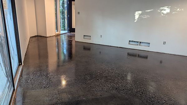 Polished concrete floor in a modern room with white walls and large windows.