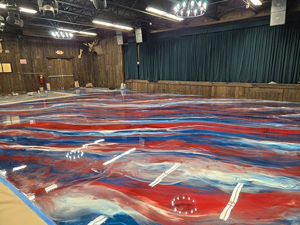 Red, white, and blue epoxy floor in a large room with a stage.