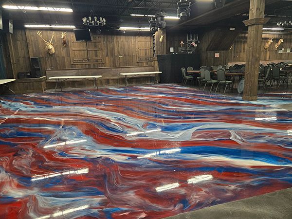 A dance floor with red, white, and blue swirls; wooden walls and tables in a dimly lit venue.