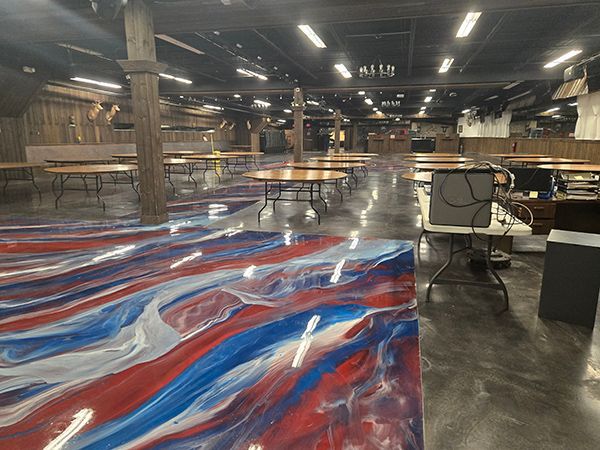 Large room with tables, a colorful red, white, and blue epoxy floor, and overhead lights.