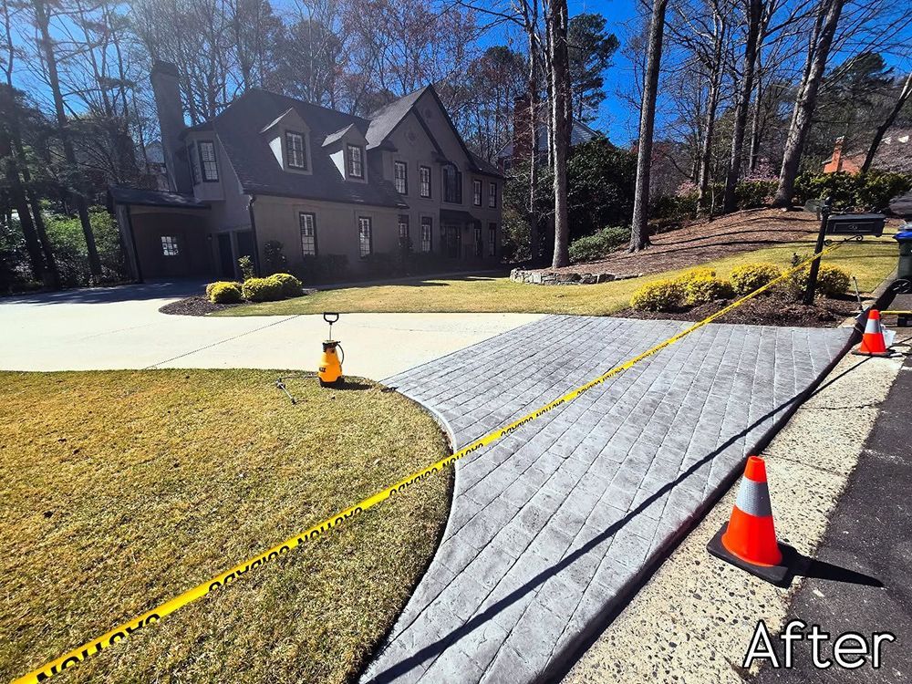 New gray paver driveway with caution tape, cones, and house in background.