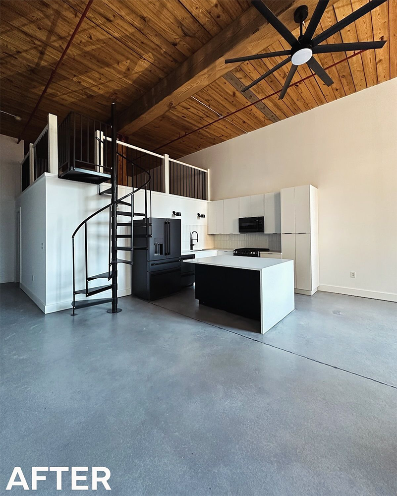 Modern loft interior after renovation: white walls, wood ceiling, black spiral staircase, kitchen island, and concrete floor.