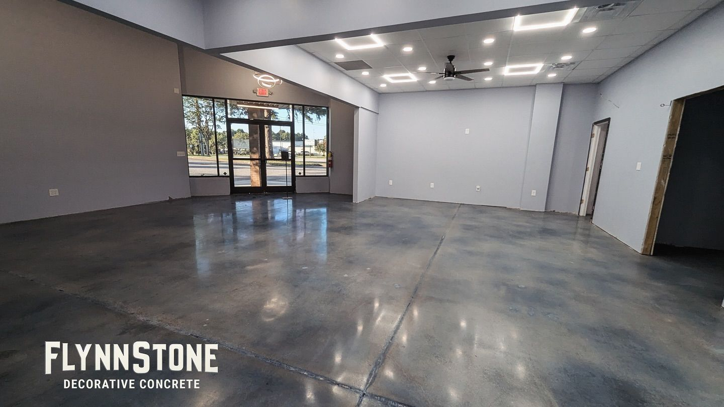 Interior of a commercial space with polished concrete floor, grey walls, and large windows. 