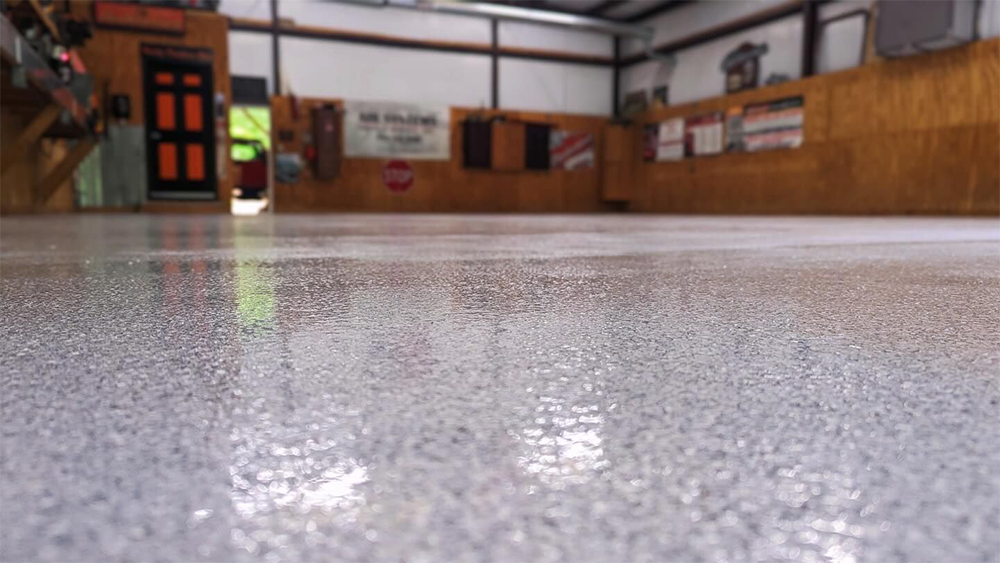 Close-up of a shiny, gray speckled epoxy floor in a workshop setting.