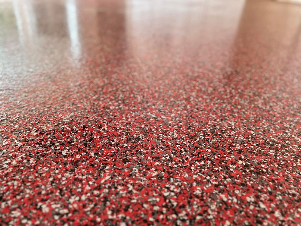 Red speckled floor, close-up with a shiny finish, reflecting light.