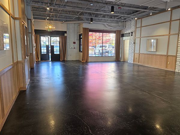 Empty room with dark floor, large windows, and light wood paneling.