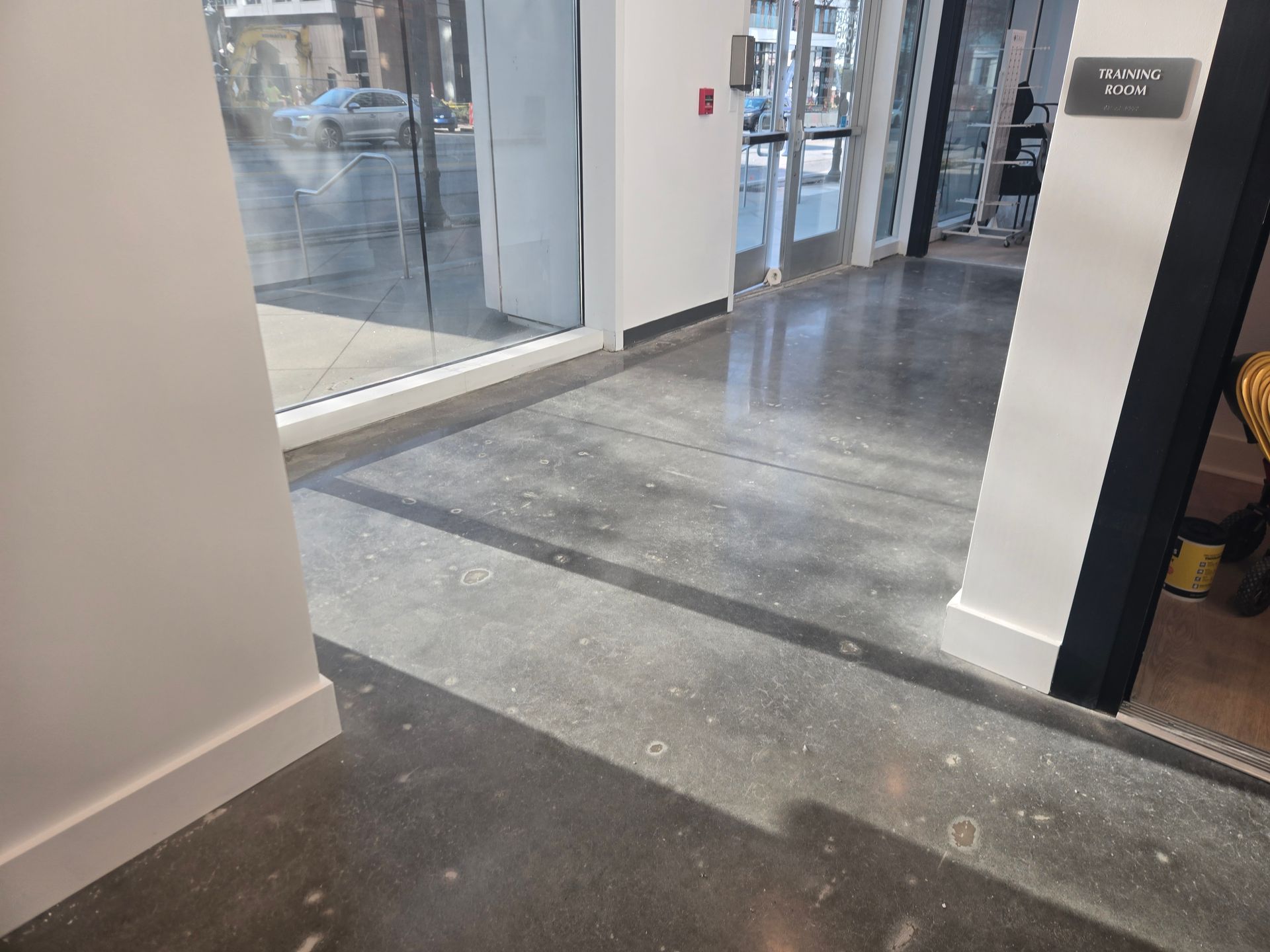 Polished concrete floor in a hallway with large windows and a glass door.