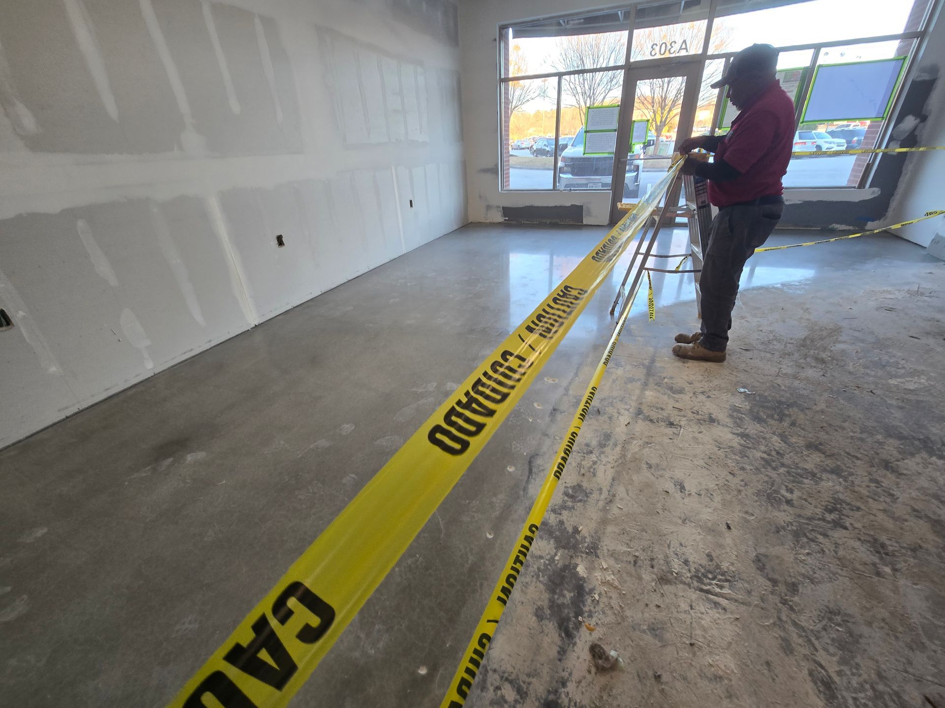 Construction site interior: a person measures with a tape in a room with caution tape.