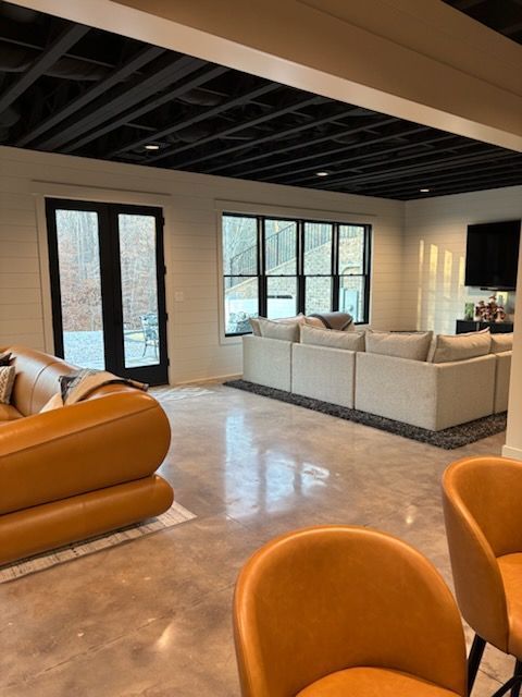 Modern living room with leather furniture, large windows, and a black ceiling.