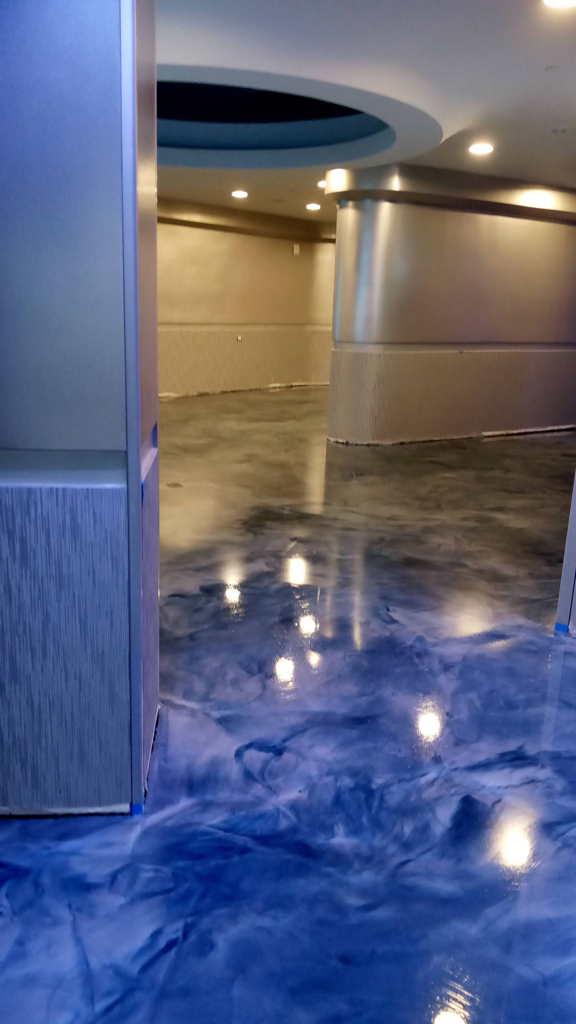 Blue and silver epoxy floor with recessed lighting, in a modern interior space