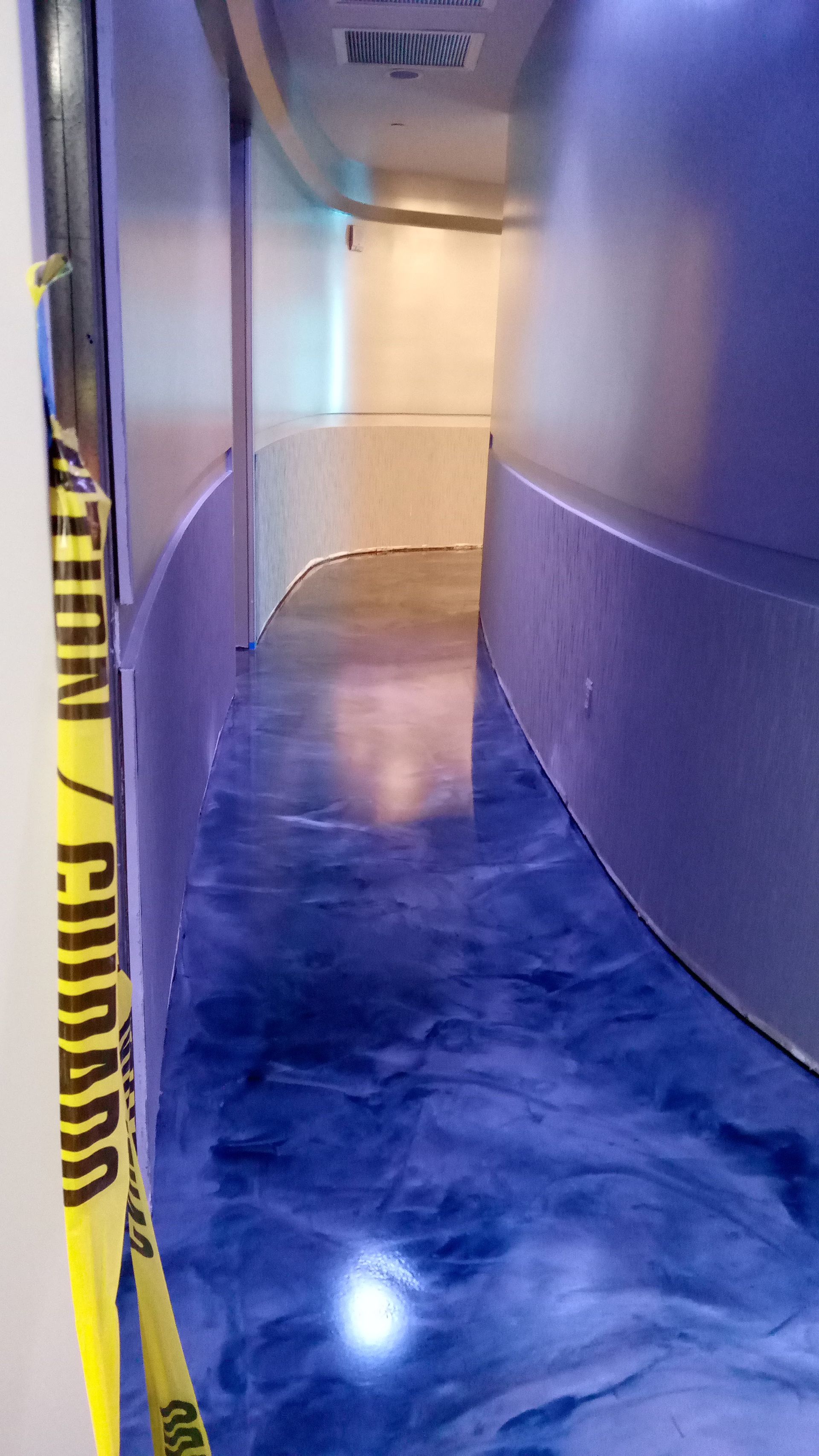 Long, curved hallway with blue epoxy floor 