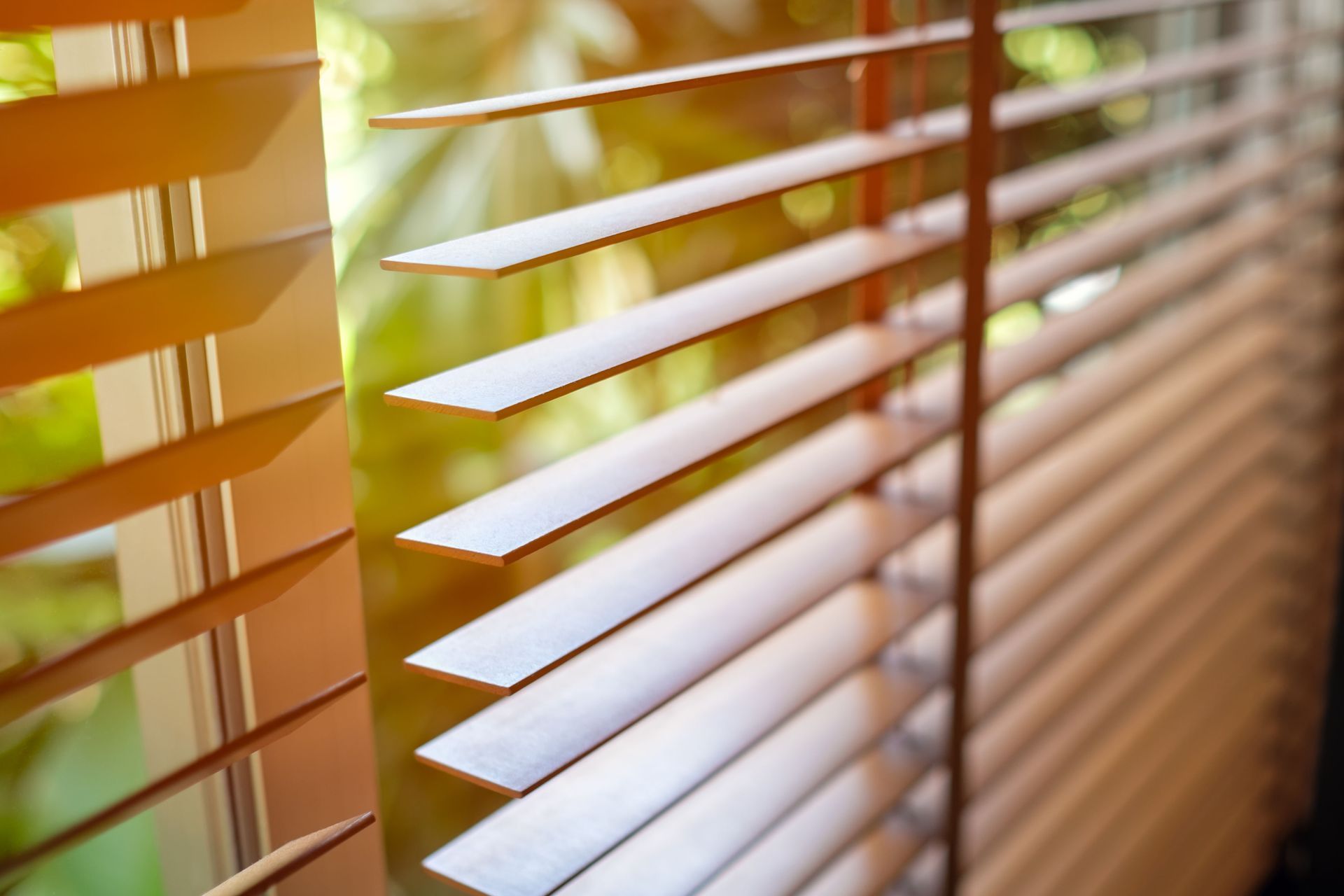 Close-up of white window blinds with warm sunlight streaming through