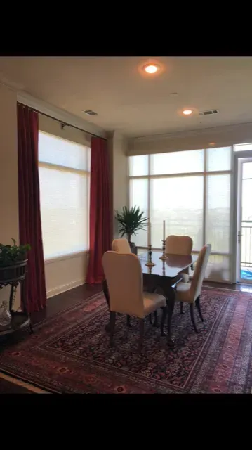 Bright dining room with a table, chairs, rug, and large windows letting in natural light
