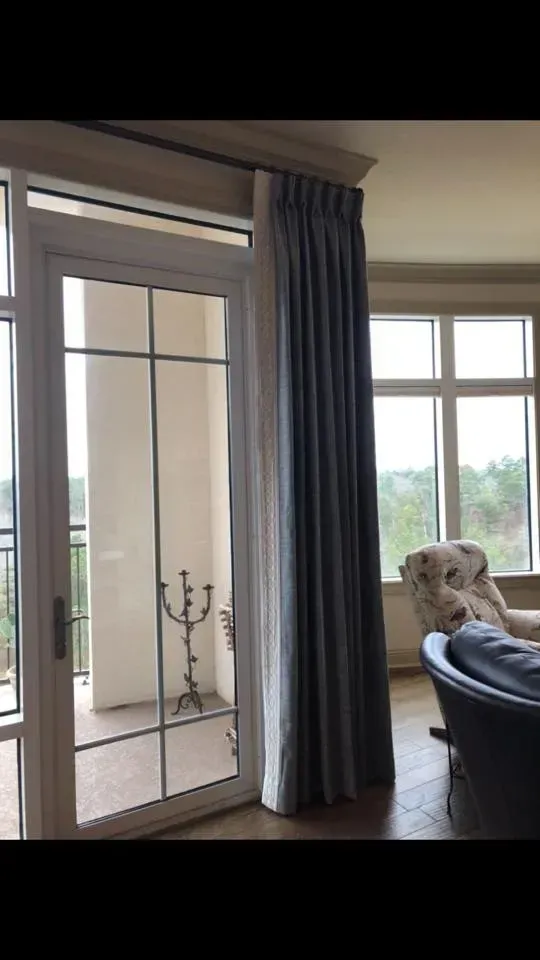Sliding glass door with blue curtains, bright patio view, and a chair by the window.
