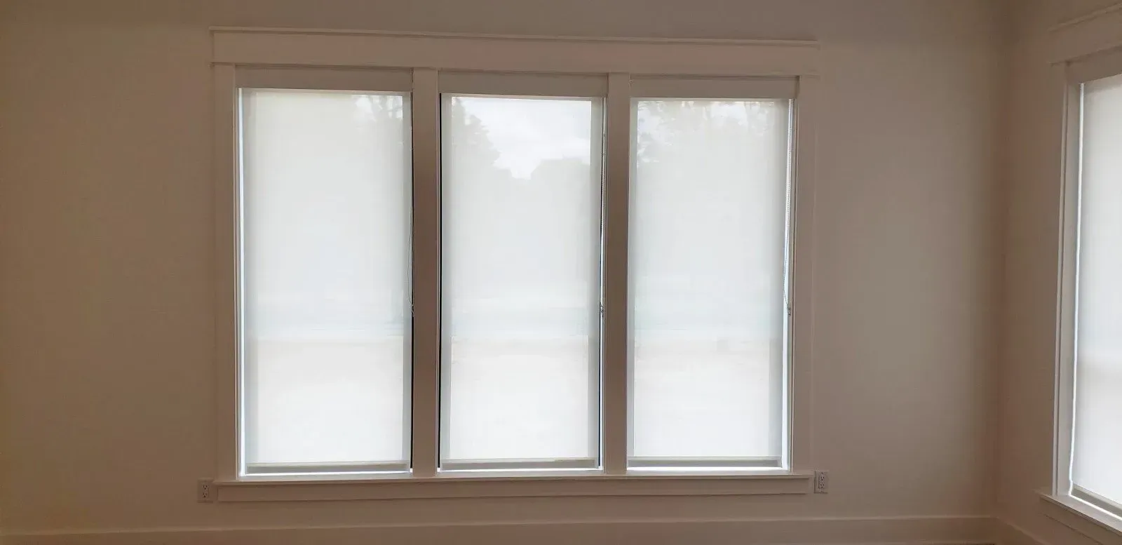 Three frosted windows in a beige room, with sunlight filtering through.