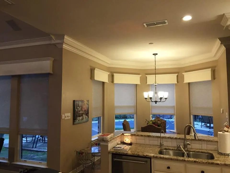 Bright kitchen with granite island, pendant lights, bay windows, and a view of a blue evening outside.