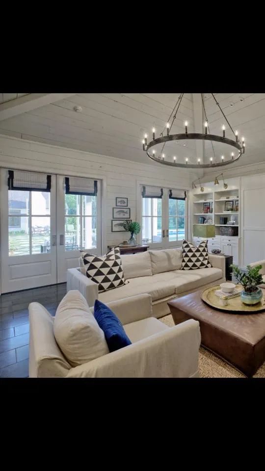 Bright living room with white sofa, round chandelier, coffee table, and large windows.