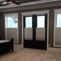 Bedroom with a bed, carpet, windows, and black-and-white window coverings.