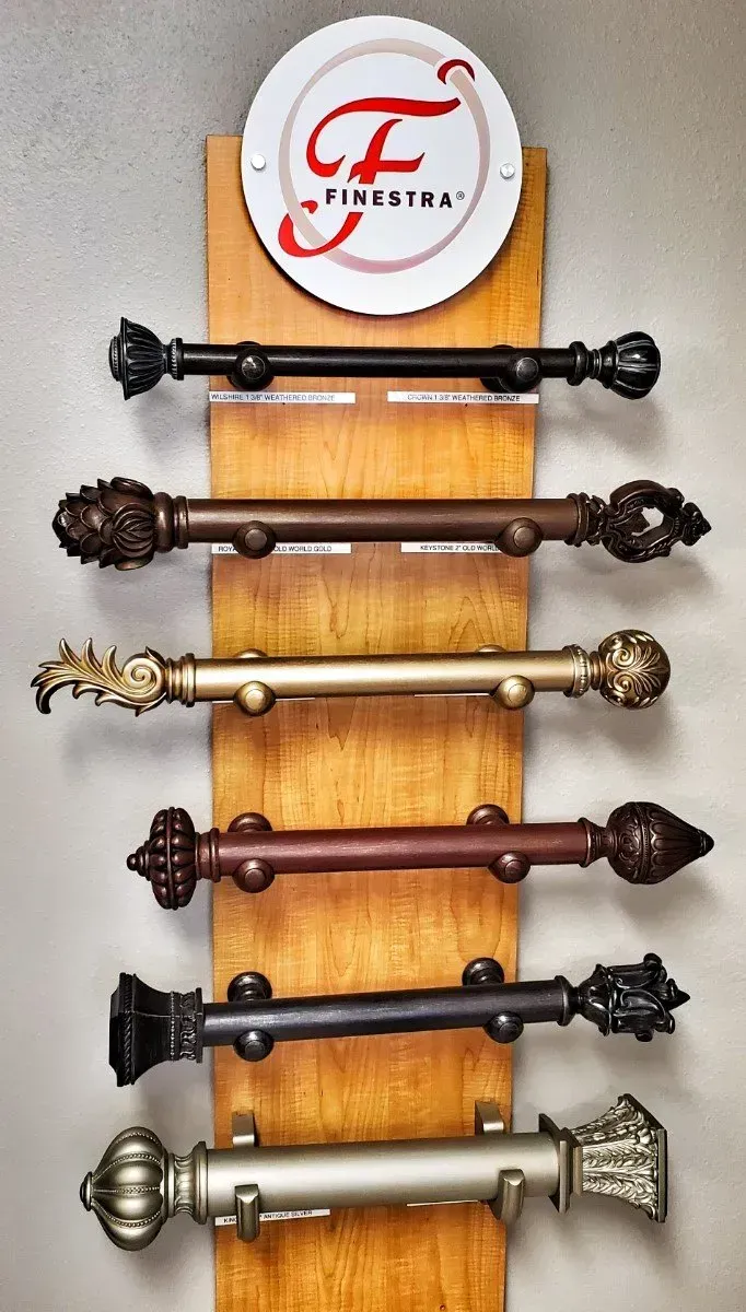 Decorative wall display of six colored metal and wood rods beneath a small round logo plaque