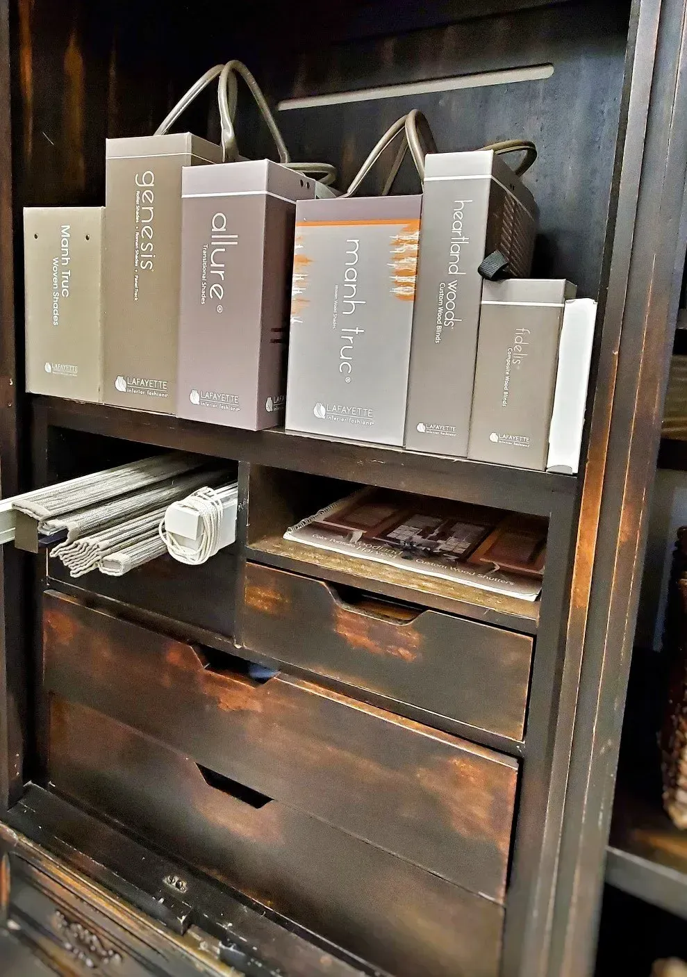 Wooden shelf with gray gift bags, folded towels, and a drawer in a dark room