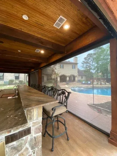 Covered patio bar with stools overlooking a backyard pool and house