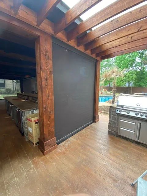 Covered outdoor patio with wood beams, wet floor, grill, and screened opening to a pool area