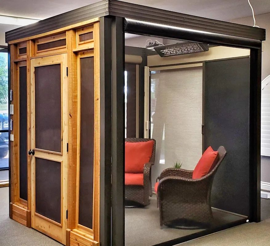 Glass-enclosed lounge booth with red chairs and wooden trim in an office setting