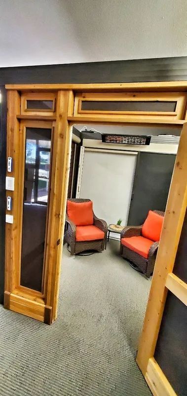 Wooden doorway opening to a carpeted room with two orange armchairs facing each other