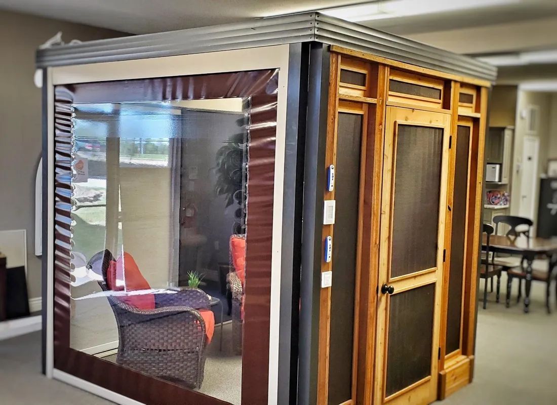 Transparent modular workspace pod with black trim and wood-framed window panels in an office lounge