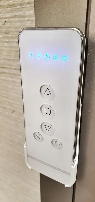 Illuminated white elevator control panel with floor indicator and arrow buttons on a wall