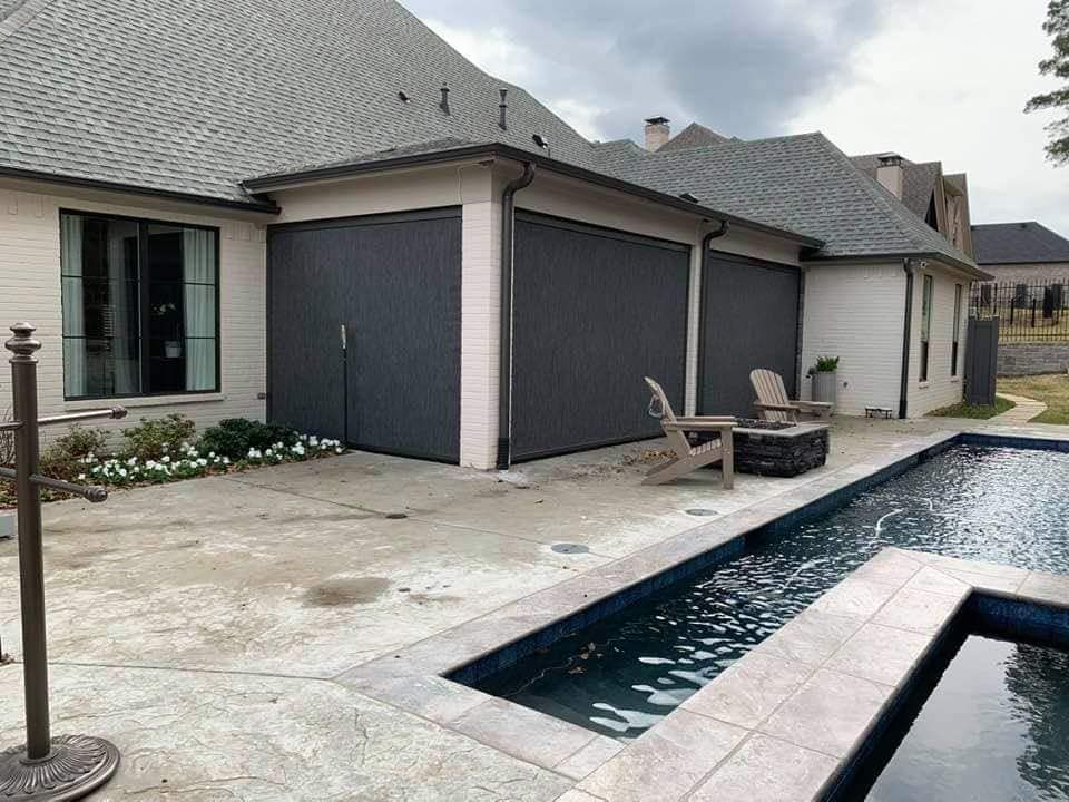 Patio with a sleek rectangular pool beside a modern house and outdoor seating area