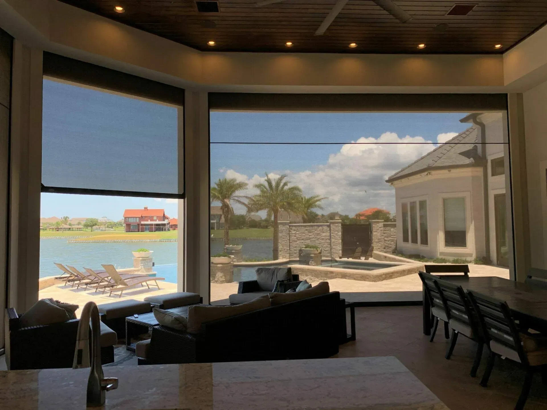 Bright beachside lounge with large windows overlooking palm trees, sand, and water