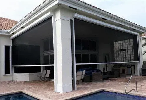 Covered patio with screened enclosure, white columns, and outdoor seating beside a pool