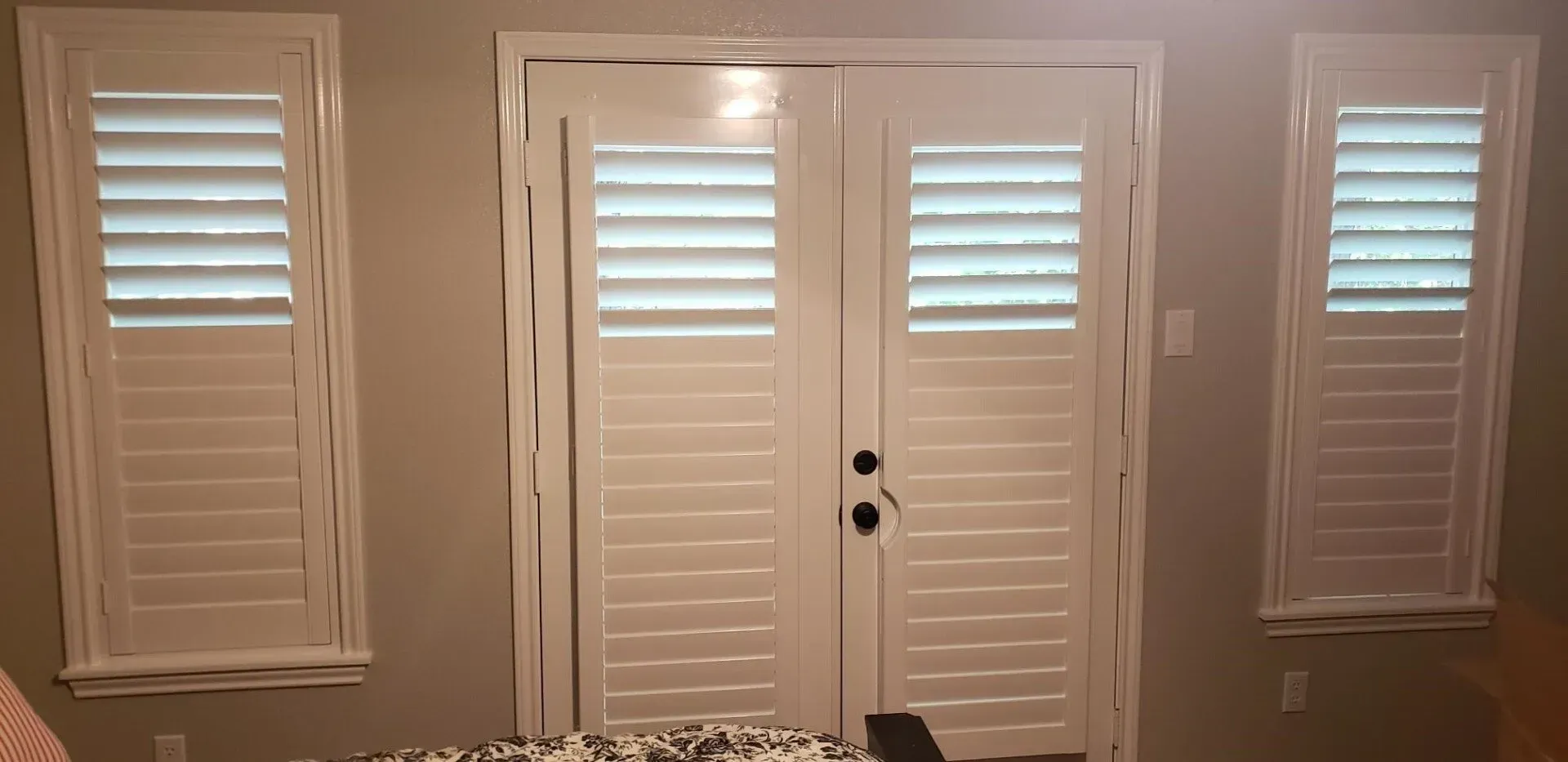 Interior wall with four white plantation-shutter windows and a central white door